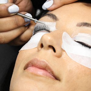 Woman receiving lash lift treatment on eyes. A transparent pad placed on top of the woman's eyelid holds lashes in an upright position.