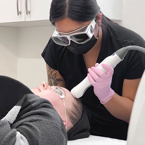 laser technician student practising on female client's forehead.