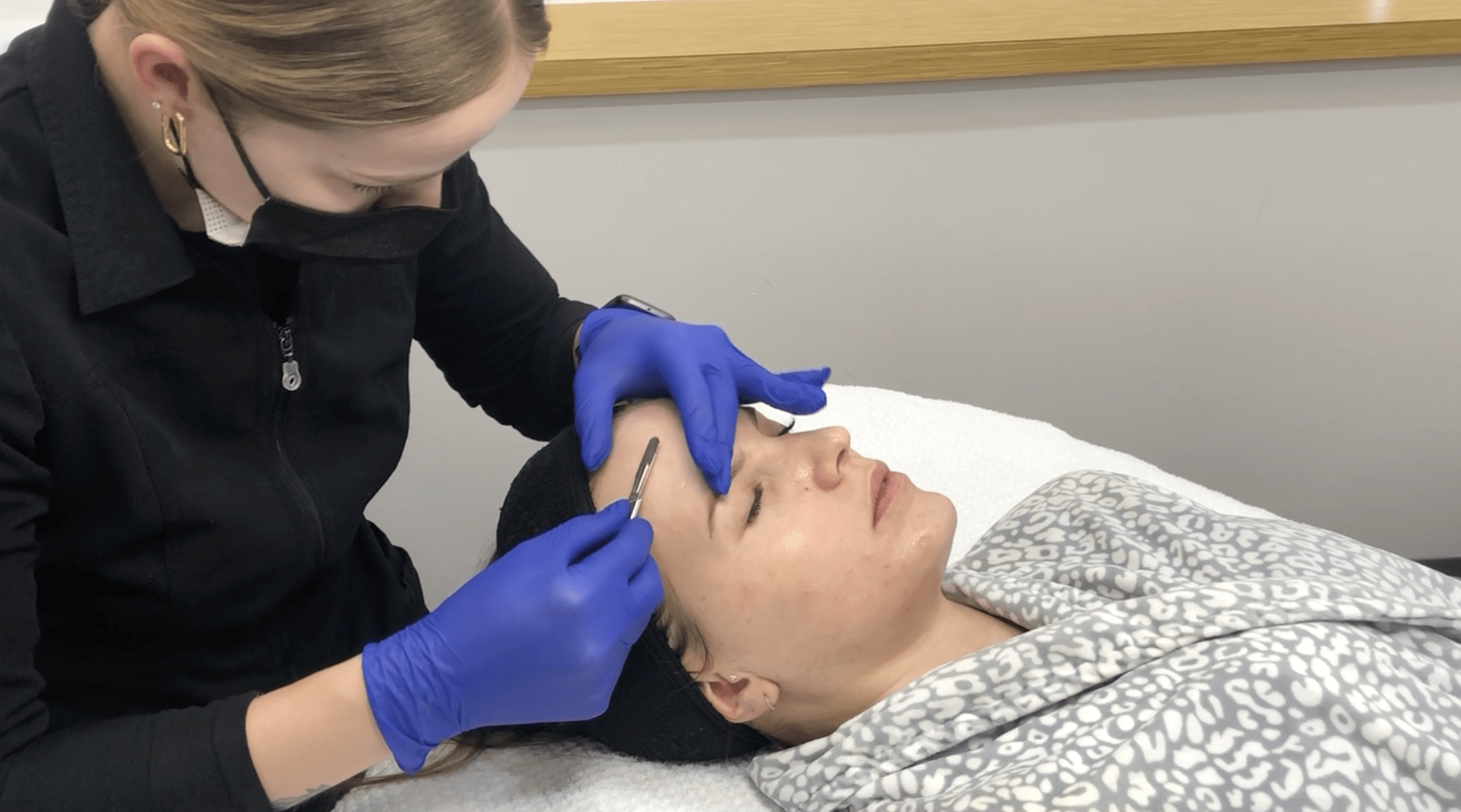 Esthetician performing a dermaplaning service on a client