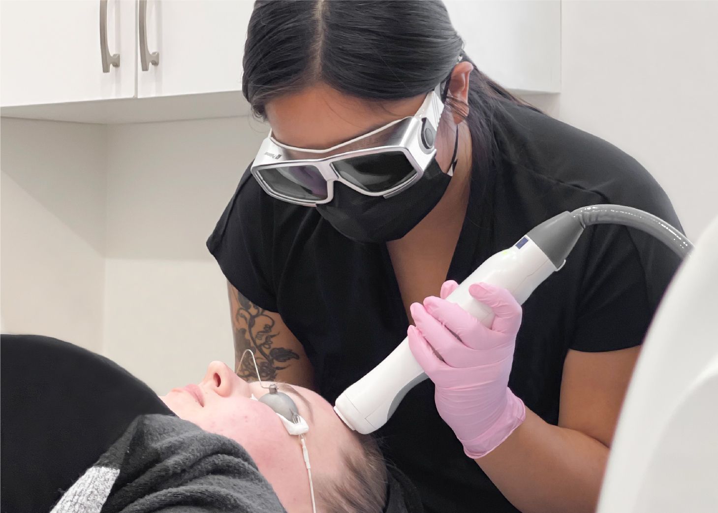 Student performing laser treatment on client's forehead