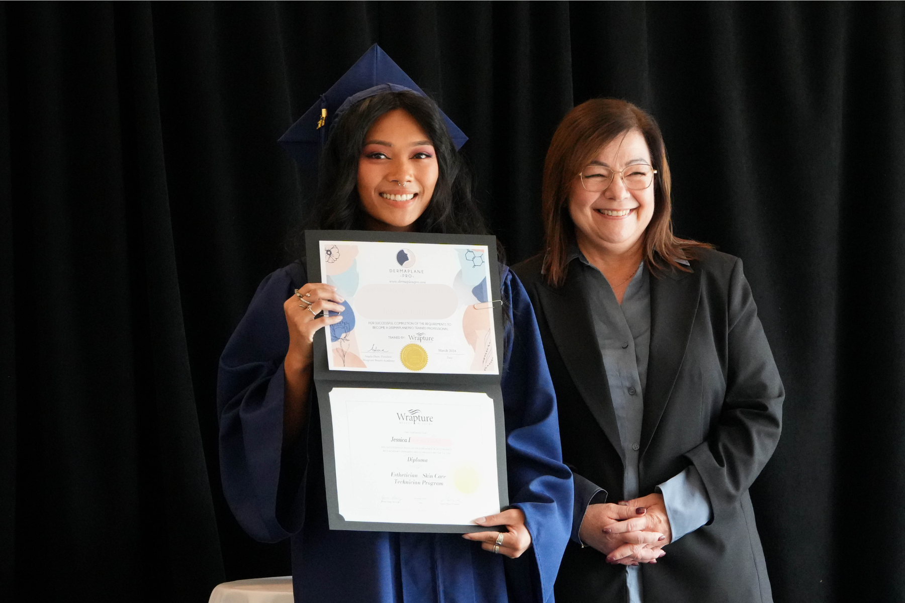 Graduate posing with faculty member at Wrapture Beauty Academy Winnipeg during their diploma ceremony.