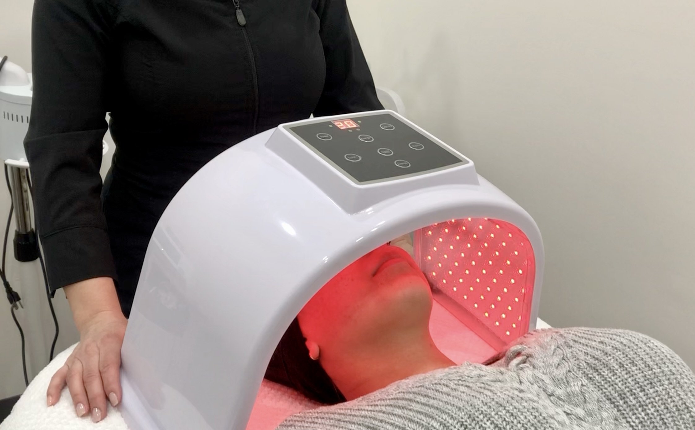 A close-up of a skin technician delivering red light therapy, focusing on care and precision.
